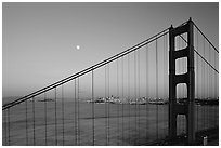 The city seen through the cables of the Golden Gate bridge, sunset. San Francisco, California, USA (black and white)