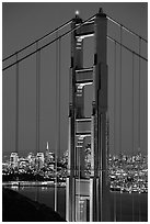 The city seen through the cables and pilars of the Golden Gate bridge, night. San Francisco, California, USA ( black and white)