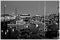 Fishing boat in  Fisherman's Wharf, with Alioto's in the background, dusk. San Francisco, California, USA (black and white)