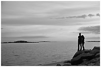 Couple standing on rock and Atlantic Ocean at sunset, Westbrook. Connecticut, USA (black and white)