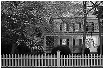 White picket fence, dogwoods, and house at dusk, Old Lyme. Connecticut, USA ( black and white)