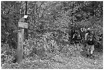 Backpackers hiking into autumn woods at Appalachian trail marker. Maine, USA (black and white)
