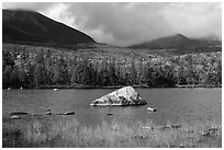 Boulder, pond, forest in autumn and mountains with clouds. Baxter State Park, Maine, USA (black and white)