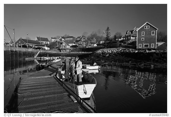 Men preparing to leave on small boat. Stonington, Maine, USA (black and white)