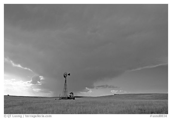 Windmill and tractor under a threatening stormy sky. North Dakota, USA