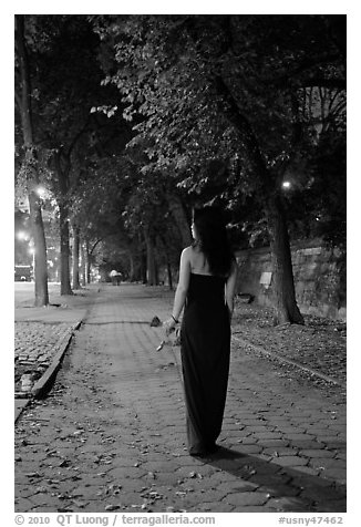 Woman in evening dress with rose on alley bordering Central Park at night. NYC, New York, USA (black and white)