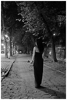 Woman in evening dress with rose on alley bordering Central Park at night. NYC, New York, USA ( black and white)