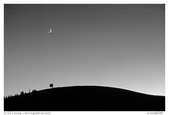 Curve of cinder cone, pastel sky, and moon. Craters of the Moon National Monument and Preserve, Idaho, USA (black and white)