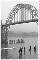 Small boat heading towards ocean under Yaquina Bay Bridge. Newport, Oregon, USA (black and white)