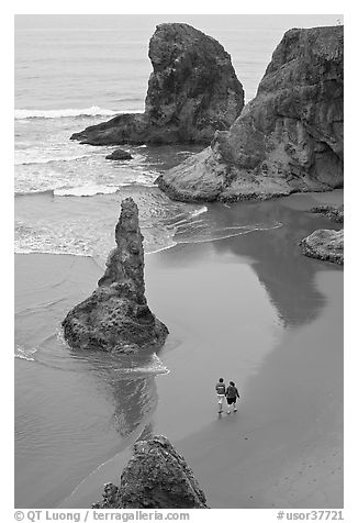 Women walking on beach among rock needles. Bandon, Oregon, USA (black and white)