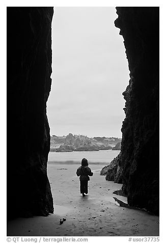 Infant standing at sea cave opening. Bandon, Oregon, USA (black and white)