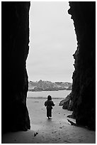 Infant standing at sea cave opening. Bandon, Oregon, USA (black and white)