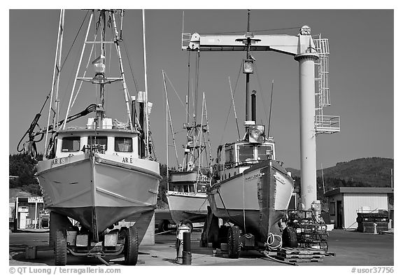Fishing boats parked on deck with hoist behind, Port Orford. Oregon, USA (black and white)