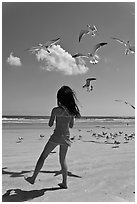 Girl playing with seabirds, Jetty Park beach. Cape Canaveral, Florida, USA (black and white)