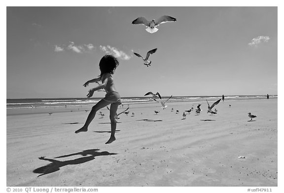Girl jumping on beach with seagulls flying, Jetty Park. Cape Canaveral, Florida, USA