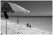 Beach with unbrella, children playing and woman strolling,. The Keys, Florida, USA (black and white)