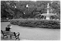 Forsyth Park Fountain with woman sitting on bench with book. Savannah, Georgia, USA (black and white)