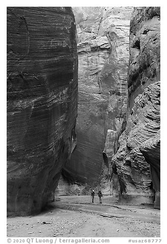 Hikers below huge walls, Paria Canyon. Vermilion Cliffs National Monument, Arizona, USA (black and white)