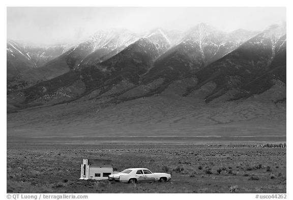 Car and pickup cover below snowy peaks. Colorado, USA (black and white)