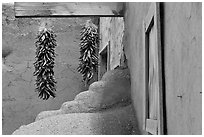 Ristras, adobe walls, and blue window. Taos, New Mexico, USA (black and white)