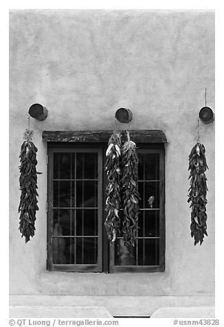 Ristras hanging from vigas and blue window. Taos, New Mexico, USA