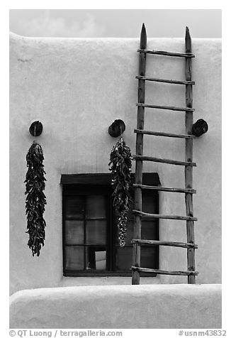 Strings of red peppers and ladder on building in pueblo style. Taos, New Mexico, USA