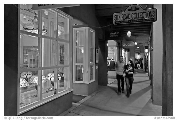 Couple walking by night in front of gallery. Santa Fe, New Mexico, USA (black and white)