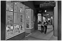 Couple walking by night in front of gallery. Santa Fe, New Mexico, USA (black and white)