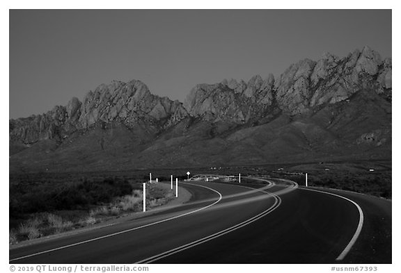 Road with light trails and Organ Mountains at dusk. Organ Mountains Desert Peaks National Monument, New Mexico, USA (black and white)