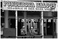 Men sitting on bench below Ponderosa Saloon sign. Virginia City, Nevada, USA (black and white)