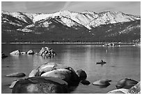 Boulders, kayak, and snowy mountains, Sand Harbor, Lake Tahoe-Nevada State Park, Nevada. USA ( black and white)