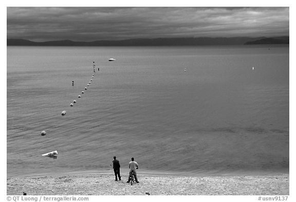 Men standing on beach under dark sky, South Lake Tahoe, California. USA (black and white)