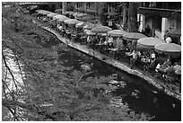 Tables under colorful umbrellas next to canal. San Antonio, Texas, USA ( black and white)