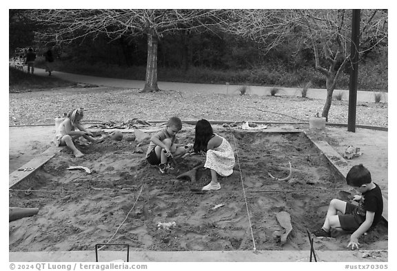 Children play in dig playground. Waco Mammoth National Monument, Texas, USA (black and white)