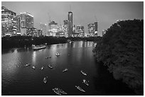 Skyline and kayaks on Colorado River at night. Austin, Texas, USA ( black and white)