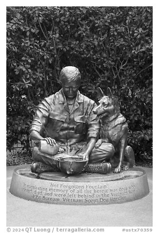 Bronze sculpture depicting Vietnam War dog handler pouring water from canteen into helmet, Military Working Dog Teams National Monument. San Antonio, Texas, USA (black and white)