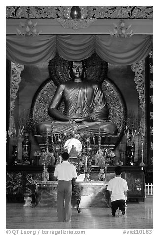 Men worshipping in front of a large Buddha state, Xa Loi pagoda. Ho Chi Minh City, Vietnam