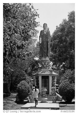 Woman praying under a large buddhist statue. Ho Chi Minh City, Vietnam (black and white)