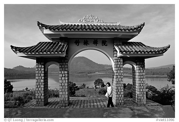 Pagoda gate with woman standing near lake. Da Lat, Vietnam