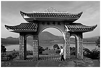Pagoda gate with woman standing near lake. Da Lat, Vietnam ( black and white)