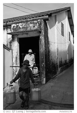 Workers carrying out containers of nuoc mam, Duong Dong. Phu Quoc Island, Vietnam (black and white)