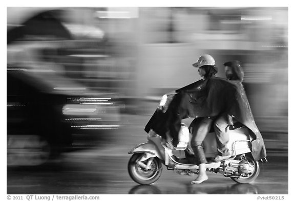 Women riding scooter in the rain. Ho Chi Minh City, Vietnam (black and white)