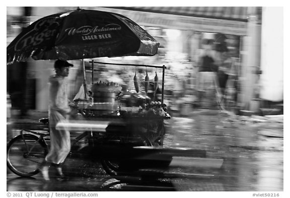 Man riding riding food cart in the rain. Ho Chi Minh City, Vietnam