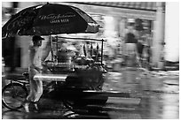 Man riding riding food cart in the rain. Ho Chi Minh City, Vietnam ( black and white)