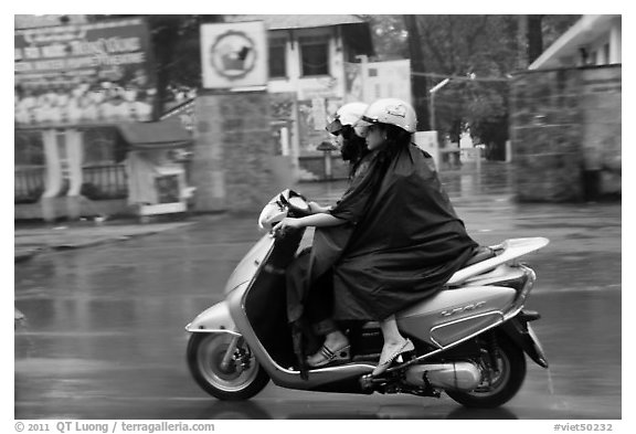 Women ride motorcycle in the rain. Ho Chi Minh City, Vietnam