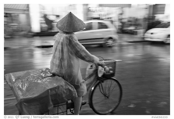 Woman rides bicycle in the rain. Ho Chi Minh City, Vietnam