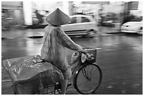 Woman rides bicycle in the rain. Ho Chi Minh City, Vietnam (black and white)