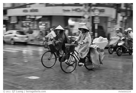 Women riding bicyles in the rain. Ho Chi Minh City, Vietnam