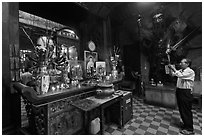 Man in prayer, with fierce statue of general behind, Jade Emperor Pagoda, district 3. Ho Chi Minh City, Vietnam ( black and white)