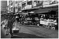 Woman carrying goods on street market. Ho Chi Minh City, Vietnam (black and white)